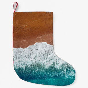 Ocean wave on a sandy beach, background  top view  small christmas stocking