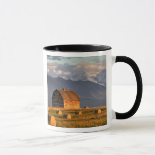 Old barn framed by hay bales and dramatic mug