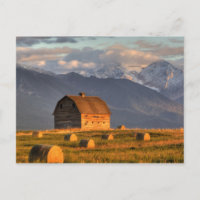 Old barn framed by hay bales and dramatic