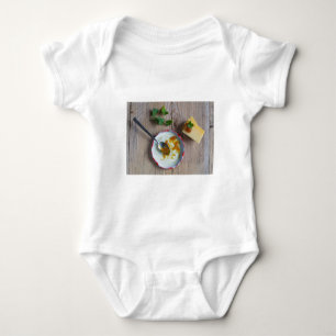 Onion pineapple chutney on rustic wood baby bodysuit
