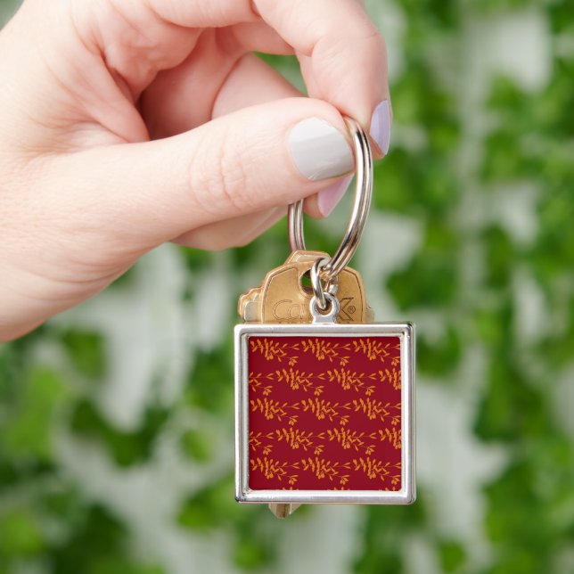 Orange silhouette branch leaves on red key ring (Hand)