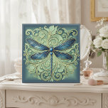 Ornate Art Nouveau Dragonfly Pat#12 Blue ID1222 Ceramic Tile<br><div class="desc">This elegant ceramic tile features a beautifully detailed Art Nouveau–inspired dragonfly, rendered in rich shades of blue with gold-accented outlines. Intricate swirling leaves and graceful botanical scrollwork surround the central motif, creating a sophisticated, ornamental look. The soft teal background gently fades toward a deep border, giving the artwork depth and...</div>