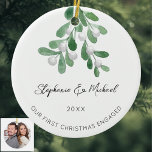 Our First Christmas Engaged Mistletoe Photo Cerami Ceramic Ornament<br><div class="desc">Celebrate your first Christmas as an engaged couple with this stylish photo ceramic ornament. 
It is decorated with watercolor mistletoe and elegant script typography.
Easily customisable. with your names,  date,  and photo.
Use the Design Tool to change the text size,  style,  or colour.
Original Watercolor © Michele Davies.</div>