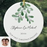 Our First Christmas Engaged Mistletoe Photo Cerami Ceramic Ornament<br><div class="desc">Celebrate your first Christmas as an engaged couple with this stylish photo ceramic ornament. 
It is decorated with watercolor mistletoe and elegant script typography.
Easily customisable. with your names,  date,  and photo.
Use the Design Tool to change the text size,  style,  or colour.
Original Watercolor © Michele Davies.</div>