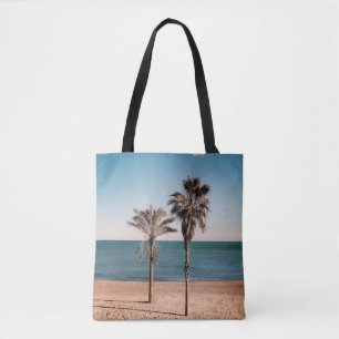 Palm tree on beach shore in the morning tote bag