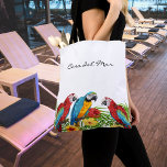 Parrots leaves summer house name tote bag<br><div class="desc">Tropical birds, parrots in blue, yellow and red sitting on green palm leaves. Decorated with tropical flowers. Elegant white as background. Template for the name of your house, beach house, or your family name, black hand lettered style script. Use your back-space key to delete if you want the bag without...</div>