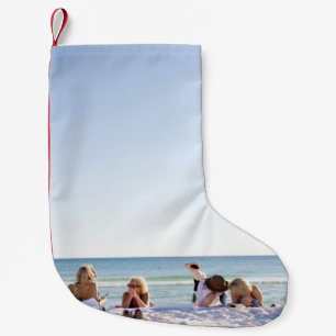 People on white sands by the beach small christmas stocking