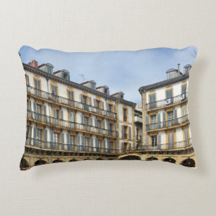 PEOPLE WALKING NEAR BEIGE CONCRETE BUILDING DURING DECORATIVE CUSHION
