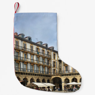 PEOPLE WALKING NEAR BEIGE CONCRETE BUILDING DURING SMALL CHRISTMAS STOCKING