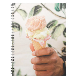 Person holding ice cream cone with three flavours  notebook