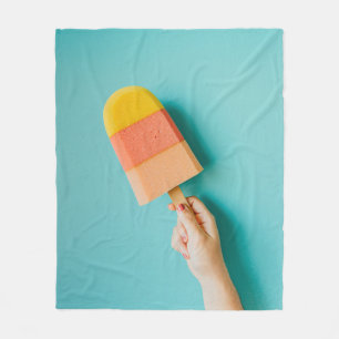 Person holding yellow and pink popsicle fleece blanket