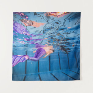 Person in purple pants lying on blue hammock tapestry