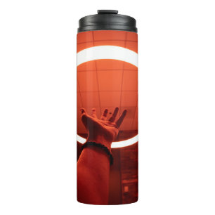 PERSON REACHING ROUND TURNED-ON FLUORESCENT LAMP I THERMAL TUMBLER