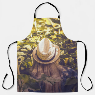 Person wearing white hat beside sunflower fields apron