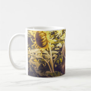 Person wearing white hat beside sunflower fields coffee mug