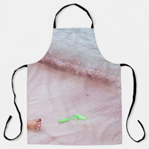 Person's foot beside green shovel on seashore apron