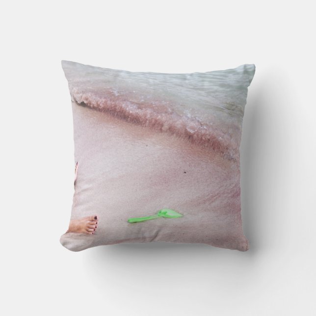 Person's foot beside green shovel on seashore cushion (Front)