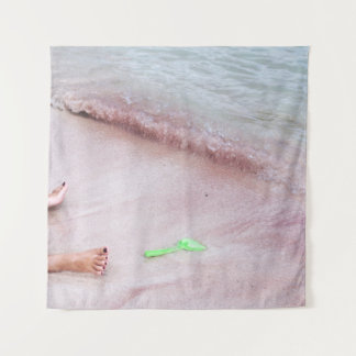 Person's foot beside green shovel on seashore tapestry