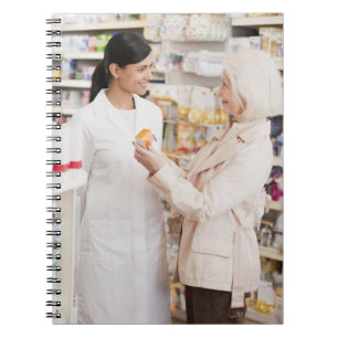 Pharmacist talking to customer in drug store notebook