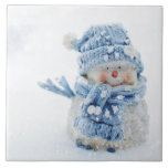 Photo of a Cute Snowman in Winter - Christmas Ceramic Tile<br><div class="desc">Ceramic tile with a cute photograph of a little snowman. Standing outside in the winter with snow falling all around. This cute little guy is dressed up in blue knitted hat and scarf.</div>