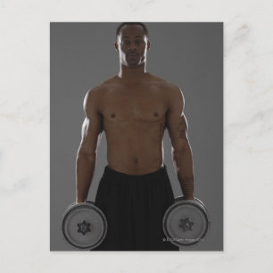 Physically fit man lifting dumbbells postcard