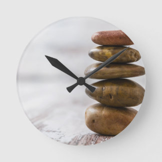 Pile of dark colored stones on white background round clock