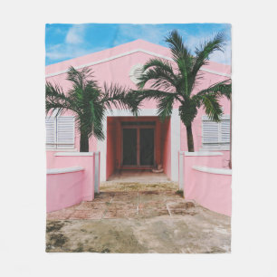 Pink and white concrete house near green trees und fleece blanket