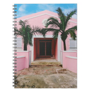 Pink and white concrete house near green trees und notebook