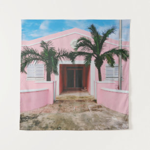 Pink and white concrete house near green trees und tapestry