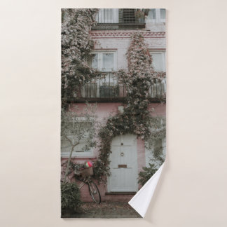 PINK AND WHITE PAINTED HOUSE COVERED WITH PLANTS A BATH TOWEL