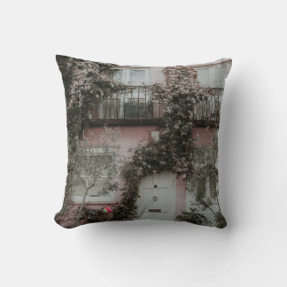 PINK AND WHITE PAINTED HOUSE COVERED WITH PLANTS A CUSHION
