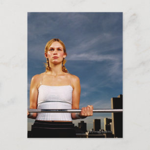 Portrait of a young woman carrying a barbell postcard