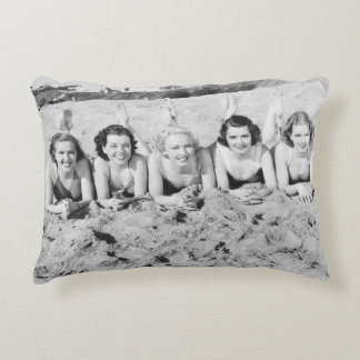 Portrait of five young women lying on the beach an decorative cushion