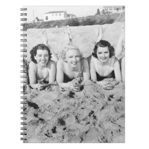 Portrait of five young women lying on the beach an notebook