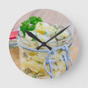 Potato salad in a jar on wooden round clock