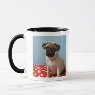 Pug puppy sitting on bed mug