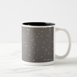 Puppy lying in snow watching snowflakes Two-Tone coffee mug