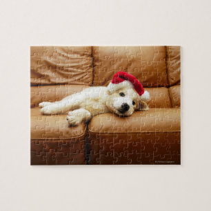 Puppy wears a christmas hat and lying on sofa jigsaw puzzle