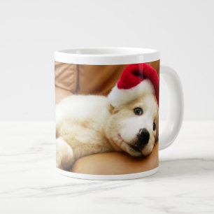 Puppy wears a christmas hat and lying on sofa large coffee mug