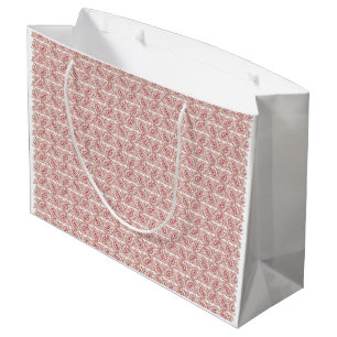 Red and pink textiles laid over a patterned rug wi large gift bag