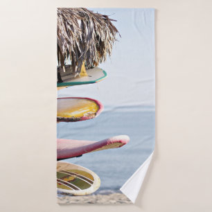 Red and white surfboard in brown wooden rack bath towel