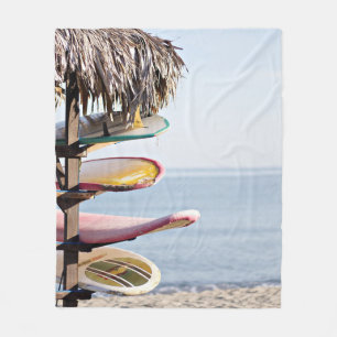 Red and white surfboard in brown wooden rack fleece blanket