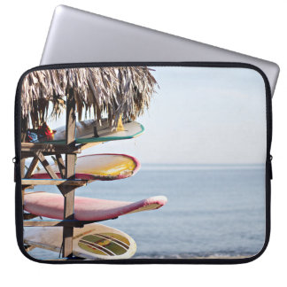 Red and white surfboard in brown wooden rack laptop sleeve