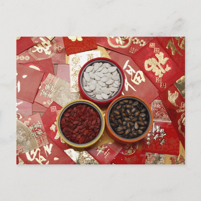 Red envelopes with melon seeds scattered on table postcard (Front)