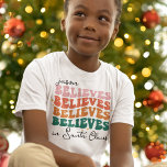 Retro believe in Santa Claus Christmas family kids T-Shirt<br><div class="desc">With its retro font style and vibrant colours,  this Christmas t-shirt brings a jolly vintage vibe to your festivities. The wording is customisable with your kid's name and reads "[name] believes in Santa Claus"</div>