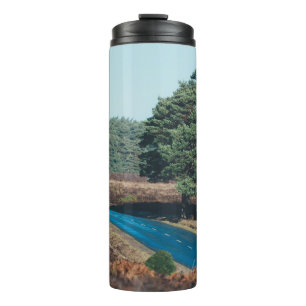 ROAD SURROUNDED WITH TREE DURING DAYTIME THERMAL TUMBLER