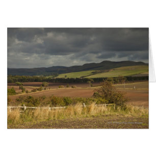 Rolling Hills And Mountains Under A Cloudy Sky