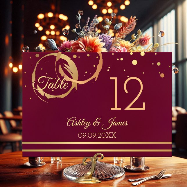Rose Gold Marsala Wine Stains Table Number Card (Table number card featuring rose gold and gold wine stain rings with sparkling confetti on burgundy)