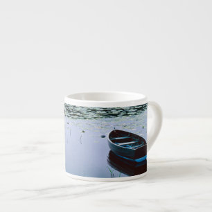 Rowboat on small lake surrounded by water espresso cup