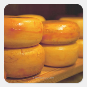 rows of colourful yellow Edam cheeses lined up Square Sticker